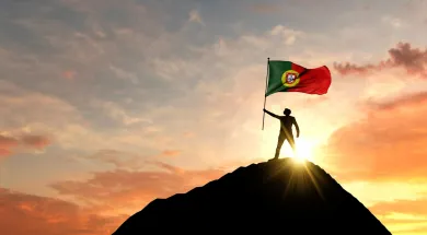 Мужчина держит флаг Португалии на вершины горы